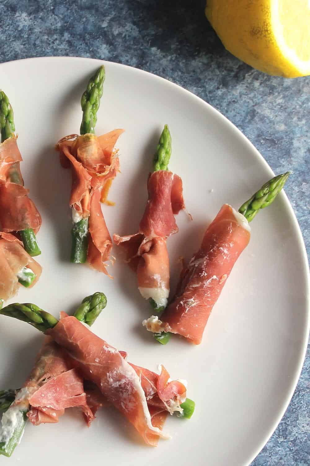 prosciutto wrapped asparagus on a white plate