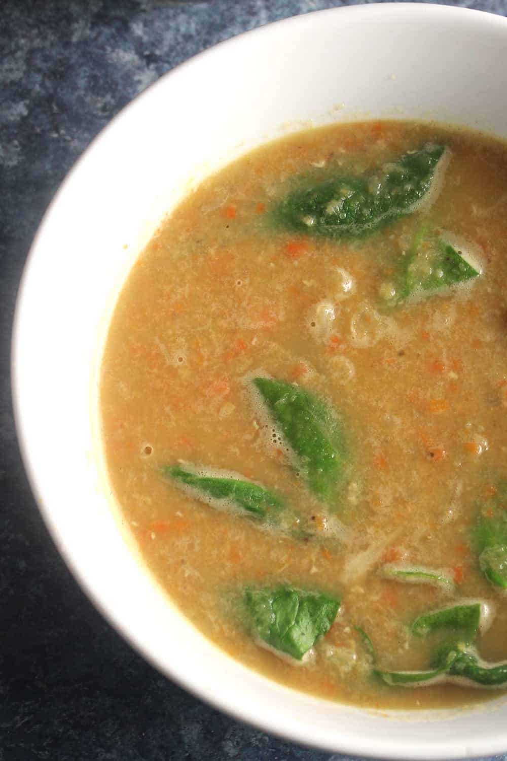 bowl of red lentil soup with spinach