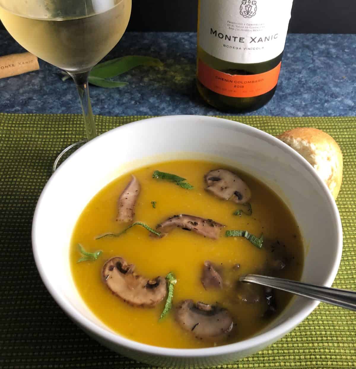 white bowl with butternut squash and mushroom soup served with white wine.