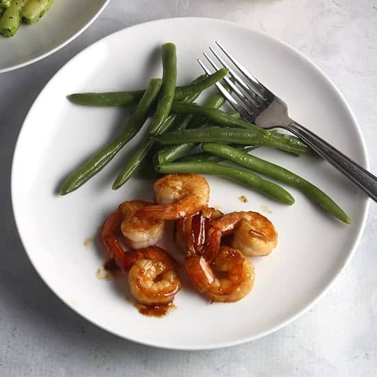 sauteed shrimp on a plate with green beans.