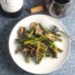 roasted asparagus with mushrooms on a white plate.