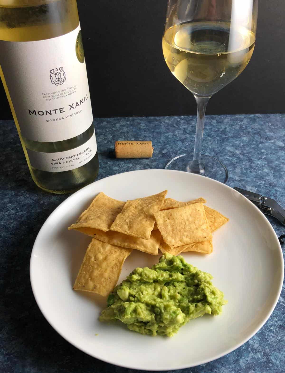 guacamole served with chips and a white wine.