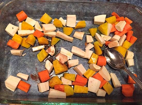 root vegetables tossed with olive oil in roasting pan.