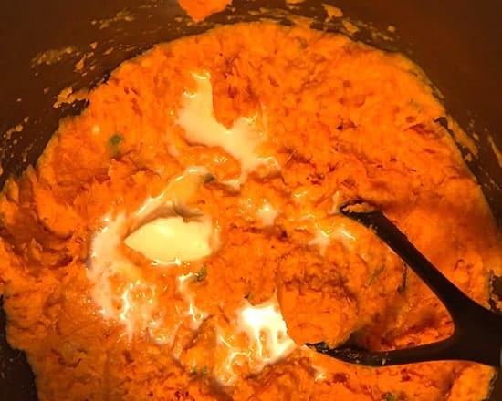 mashing sweet potatoes in a pan.