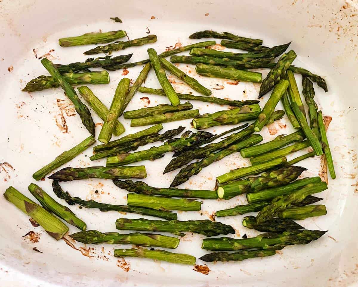 roasted asparagus in a white baking dish.