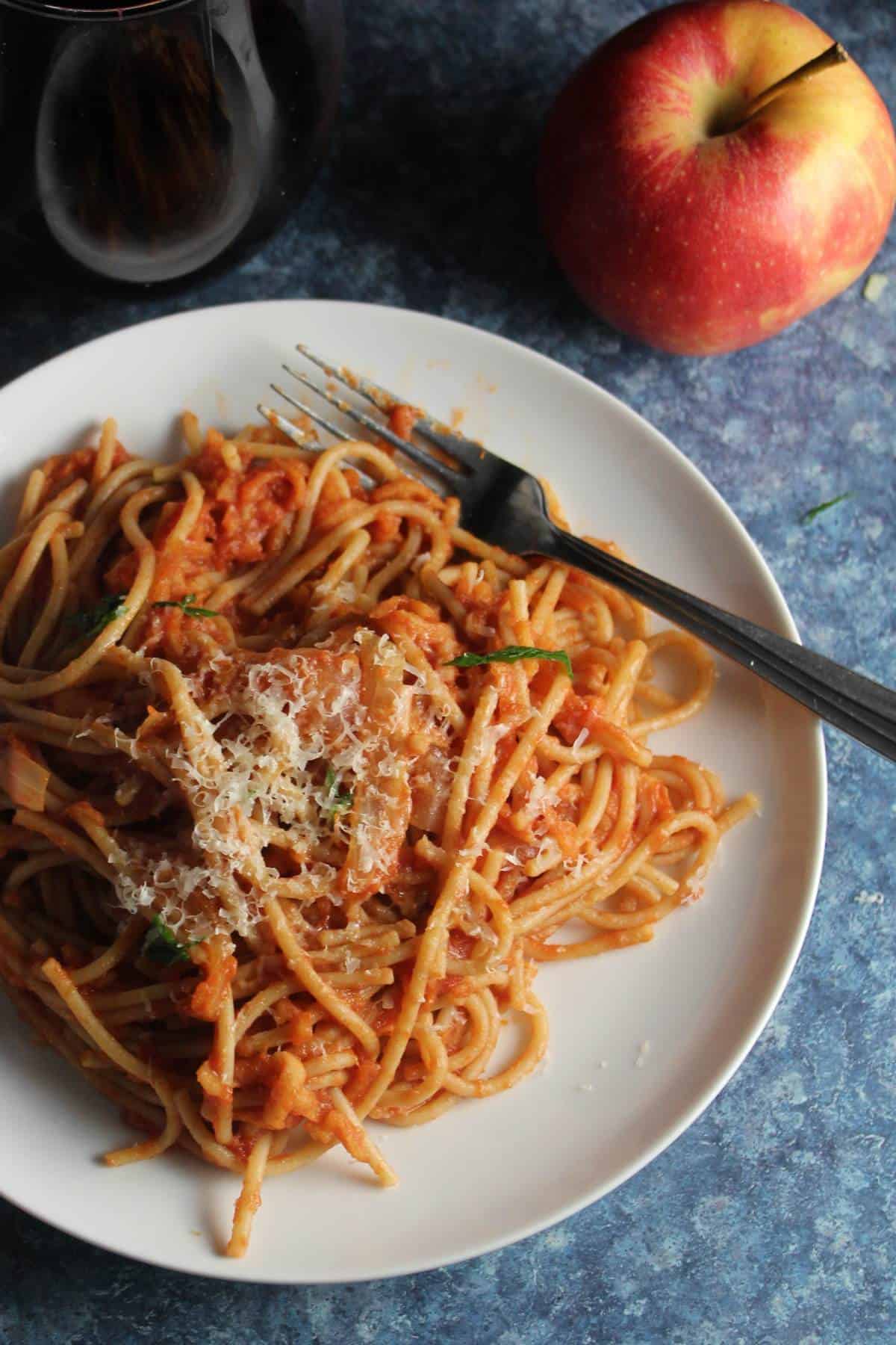 tomato apple pasta plated with an apple near the plate