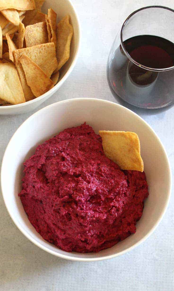 bowl of roasted beet dip with a glass of red wine.