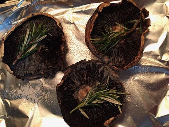 Portobello mushrooms ready to roast with sprigs of rosemary.