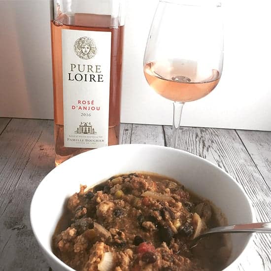 a rosé wine served with a bowl of black bean turkey chili.