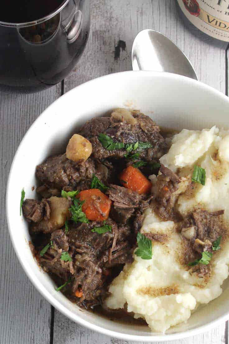 Bowl of Beef Stew with Root Vegetables served with mashed potatoes and red wine