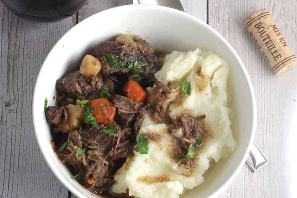 bowl of beef stew with mashed potatoes on the side.