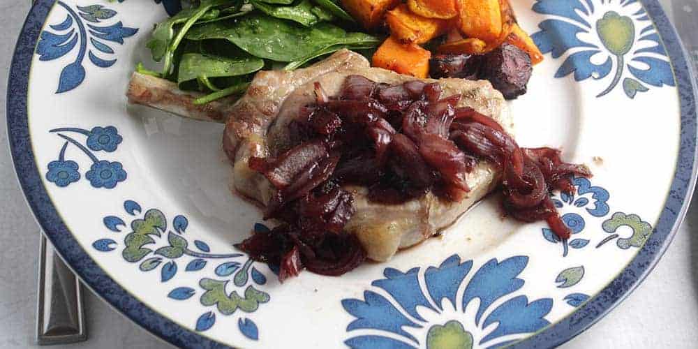 pork chop on a plate topped with pomegranate sauce.