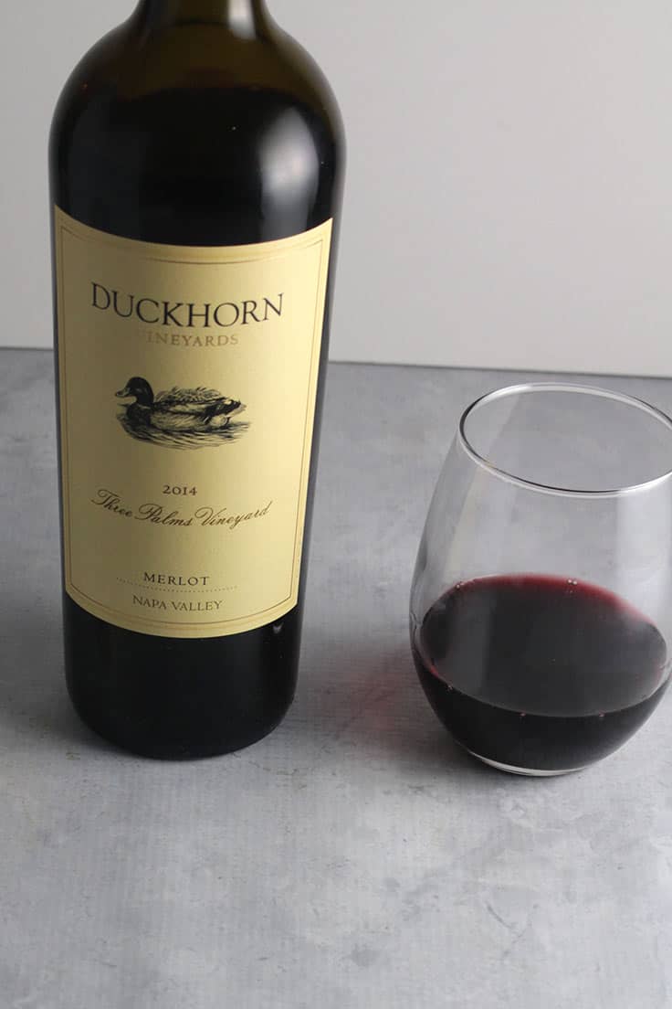 bottle of 2014 Duckhorn Three Palms Vineyard Napa Merlot with a glass of the wine next to the bottle.