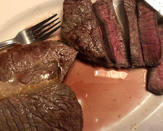 London broil steak sliced on a platter.