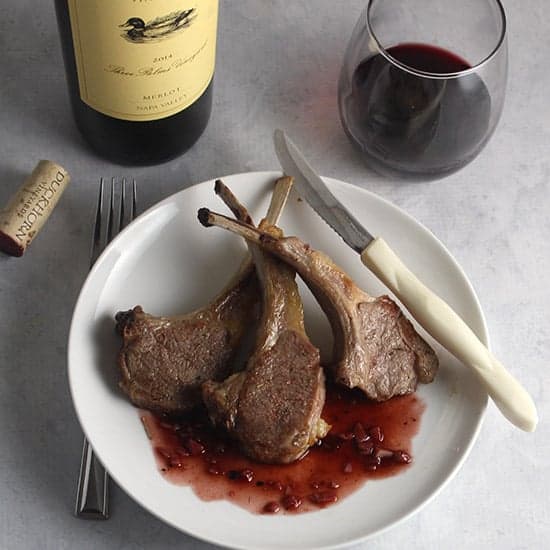 roasted lamb chops on a plate with blackberry sauce, served with a Duckhorn Merlot wine.