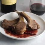 roasted lamb chops on a plate with blackberry sauce.