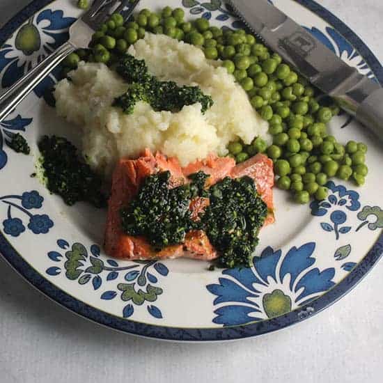 salmon topped with pesto served alongside mashed potatoes.