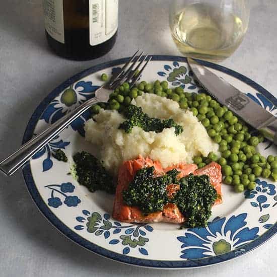 Salmon with Pesto served with potatoes, peas and a glass of white wine.