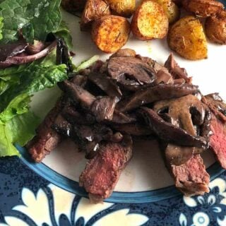 steak topped with Manchego mushroom sauce served with salad and potatoes.