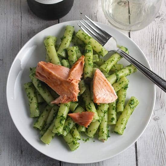 plate with pesto pasta topped with salmon