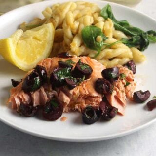 salmon topped with lemon olive relish and a side of pasta.