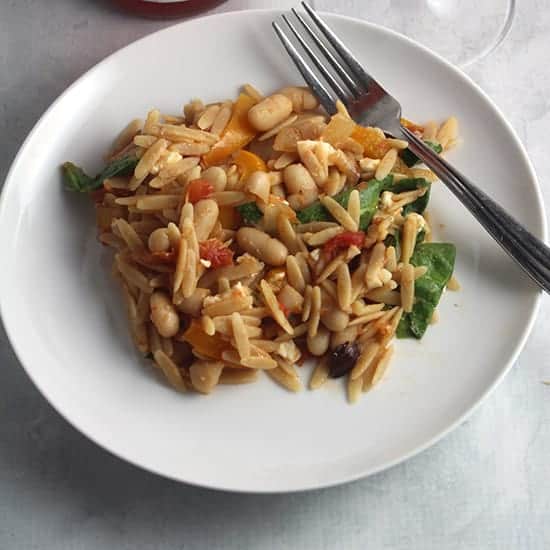 orzo with spinach, beans and vegetables on a plate.