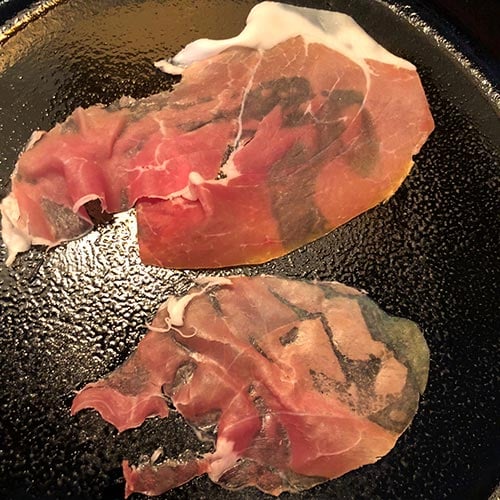 crisping prosciutto in a skillet.