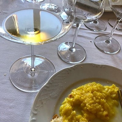 glass of Trebbiano white wine next to saffron risotto.