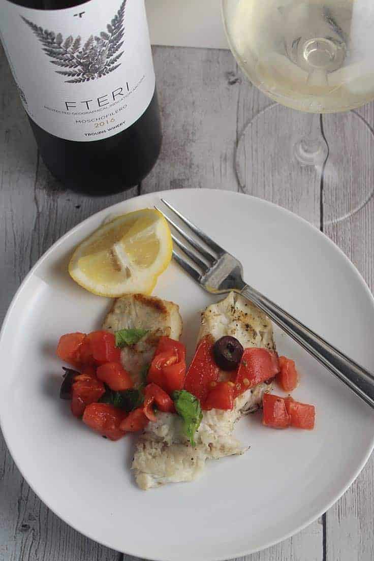 grilled tilapia topped with tomatoes and olives and paired with a Greek white wine. Delicious Greek inspired wine pairing! #grilledfish #winepairing #tilapia