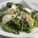 spinach and pear salad with pumpkin seeds and shredded cheese.
