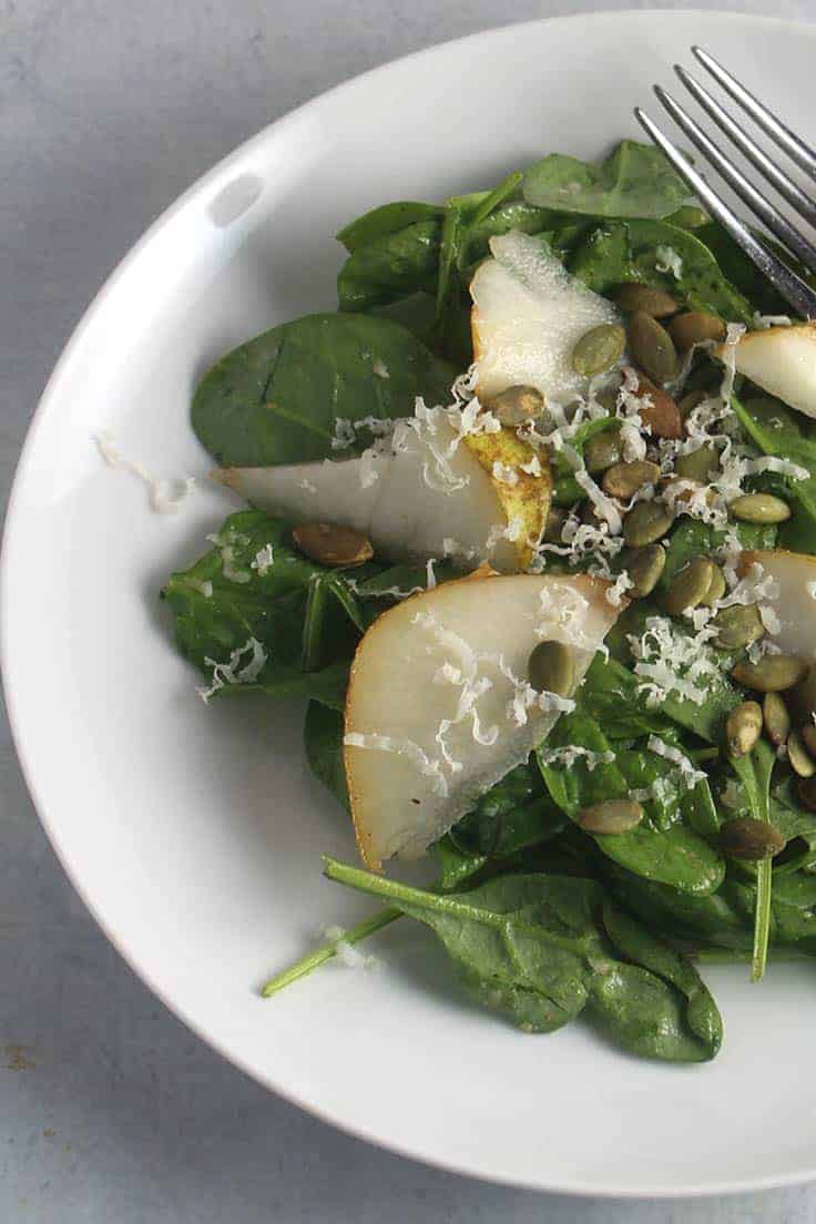 Ripe pears add great fruit flavor to a basic spinach salad. We add a touch of spice to the simple dressing for a salad that might steal the show at your dinner table! #salads #spinachsalad #pears