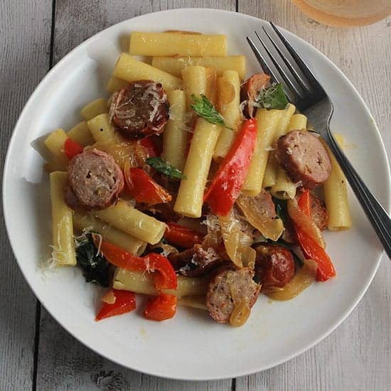 ziti with sausage, peppers and onions on a plate.