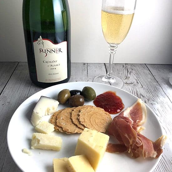 Binner Crémant d'Alsace with cheese, olives and ham on a plate.