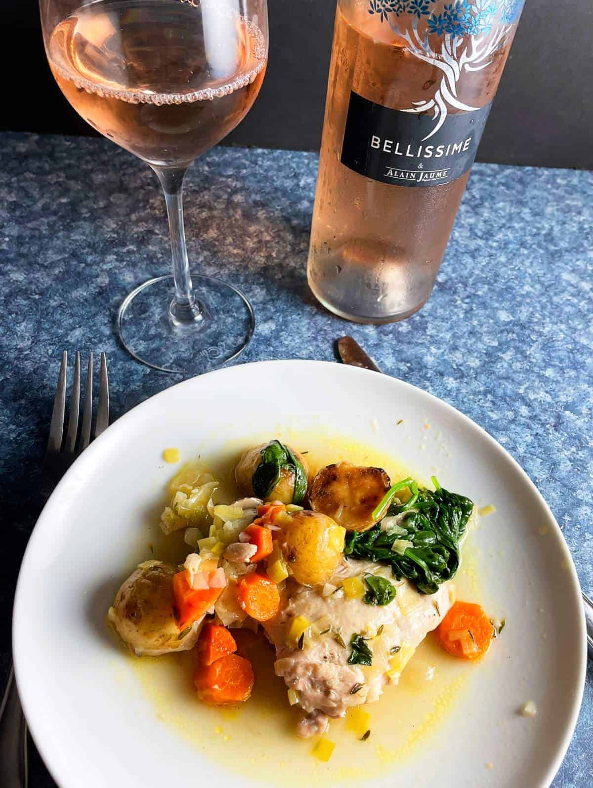boneless chicken thighs served with vegetables and a rosé wine.
