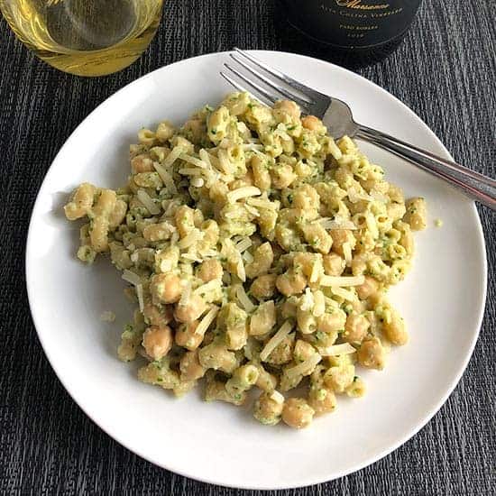 creamy cauliflower pasta with kale and chickpeas, with a glass of white wine.