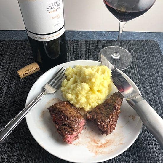 BBQ Baked Steak Tips on a plate with potatoes and red Tannat wine.