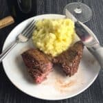 baked steak tips on a plate with mashed potatoes.