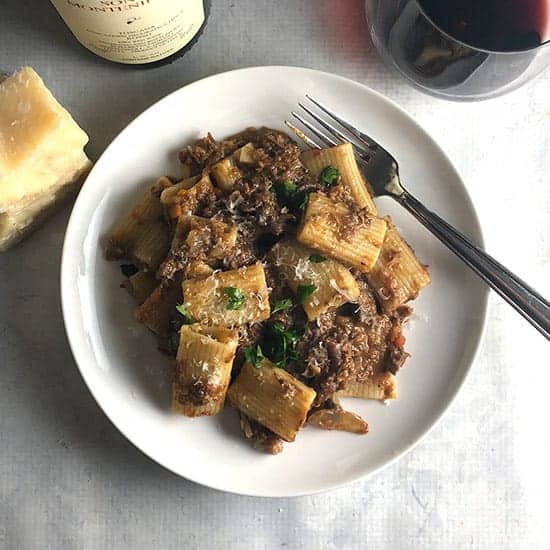 mushroom and short rib ragu on a plate serve red wine on the side.