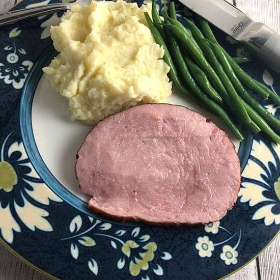 Slice of Hatfield Ham plated with potatoes and green beans.
