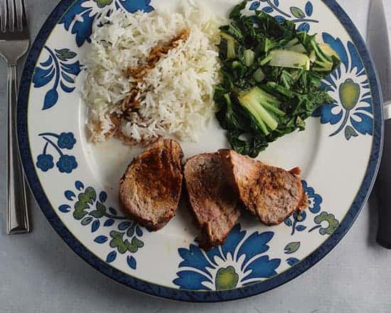 Asian Grilled Pork Tenderloin on a plate with bok choy and rice.