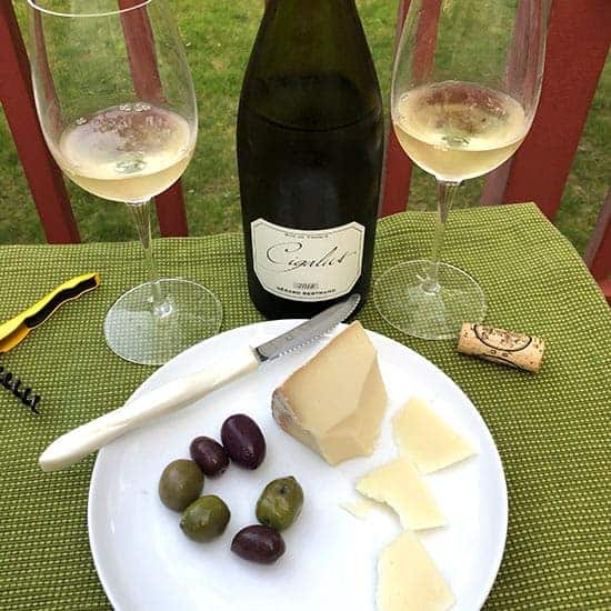 Cigalus Blanc wine with a plate of cheese and olives.