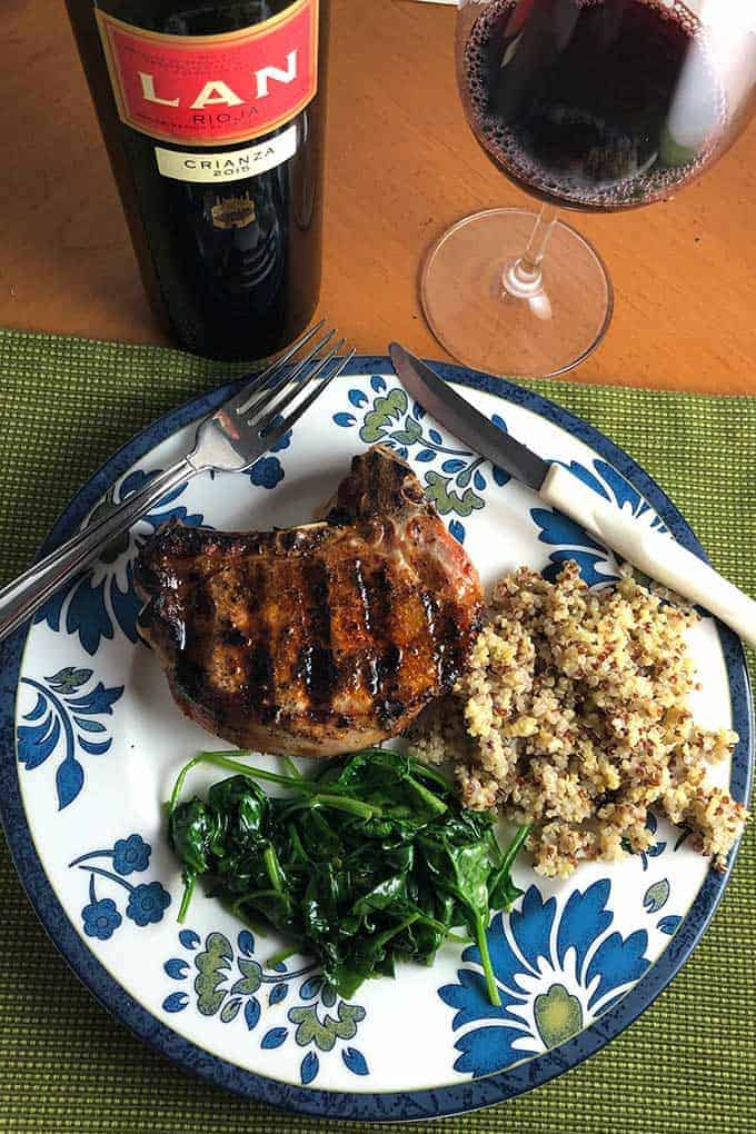 Paprika pork chops plated with spinach and quinoa with Rioja wine.