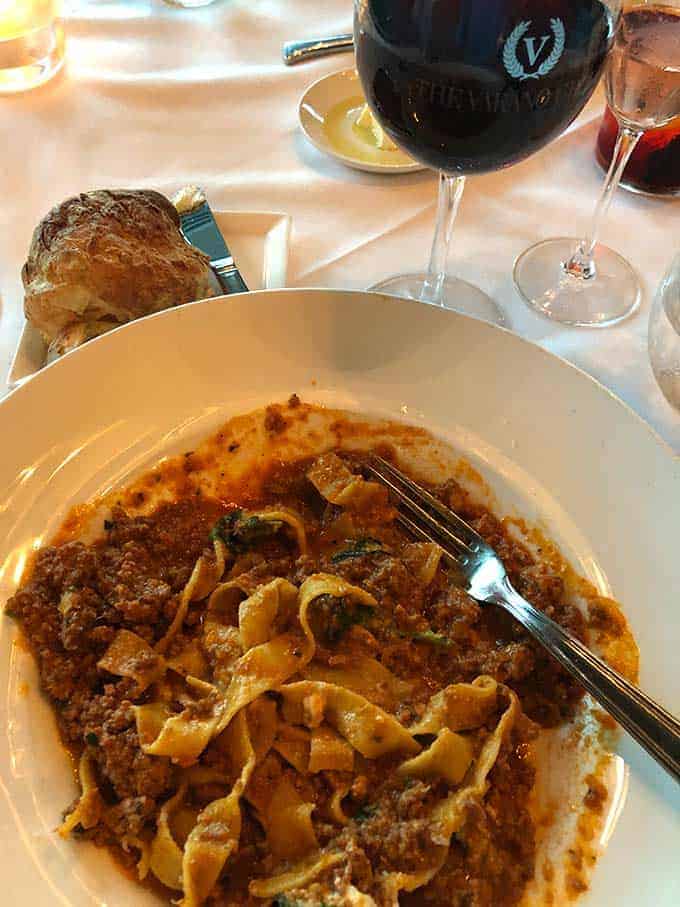 plate of Bolognese pasta with a glass of red wine.