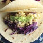 white soft tacos with roasted cauliflower, red cabbage and avocado cream.