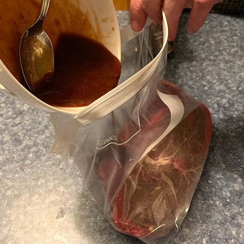 pouring marinade into bag with steak.