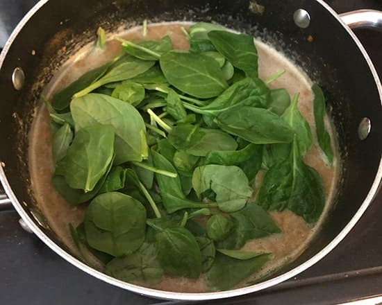 adding spinach to lentil soup.