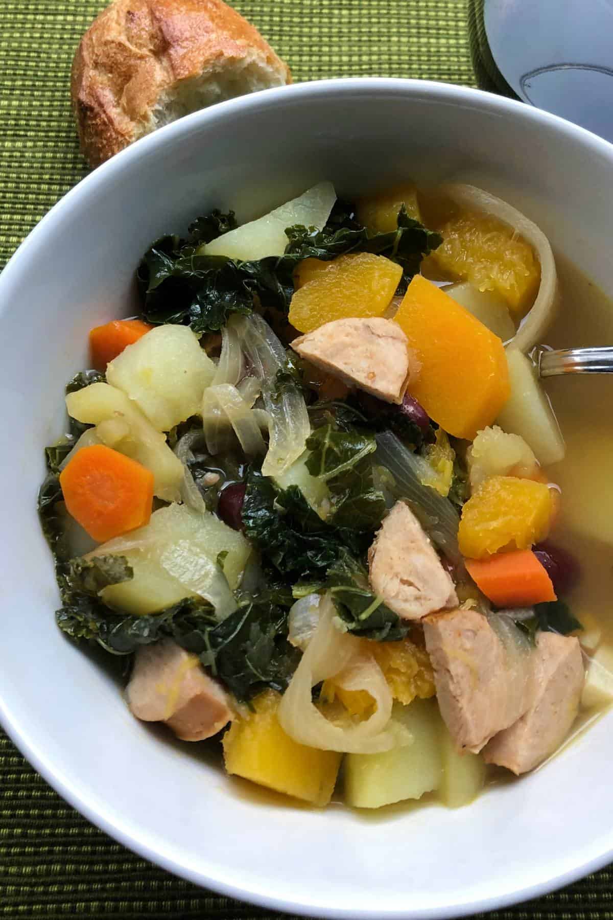 bowl of the best Portuguese Kale Soup with some crusty bread on the side.