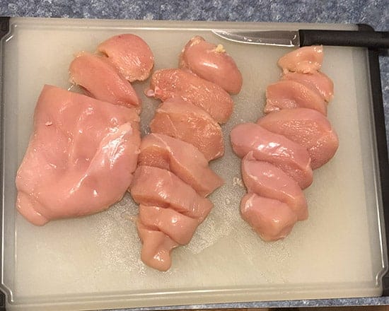 sliced raw chicken on cutting board