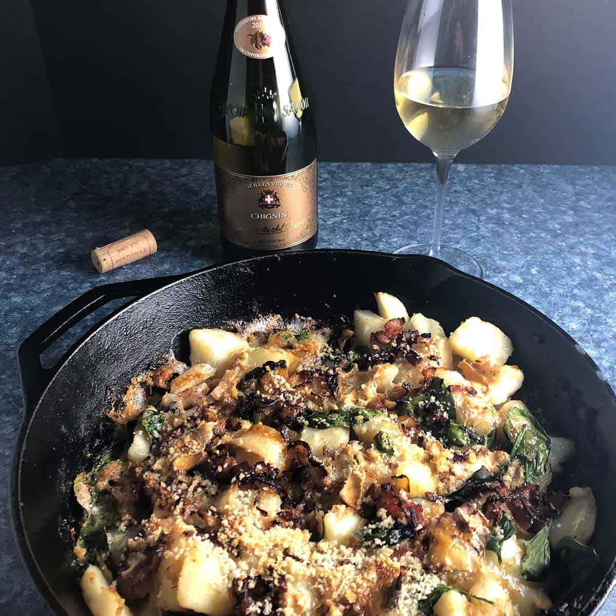 tartiflette in a skillet paired with wine.