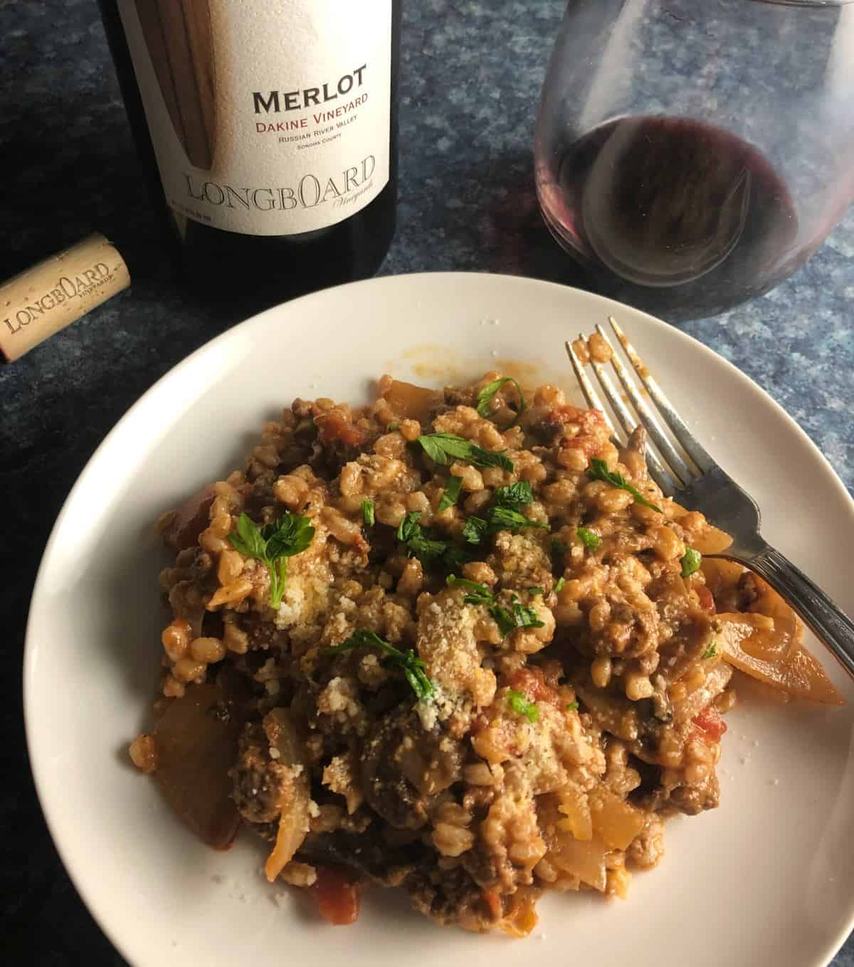 mushroom farro with ground beef on a white plate, served with red wine.